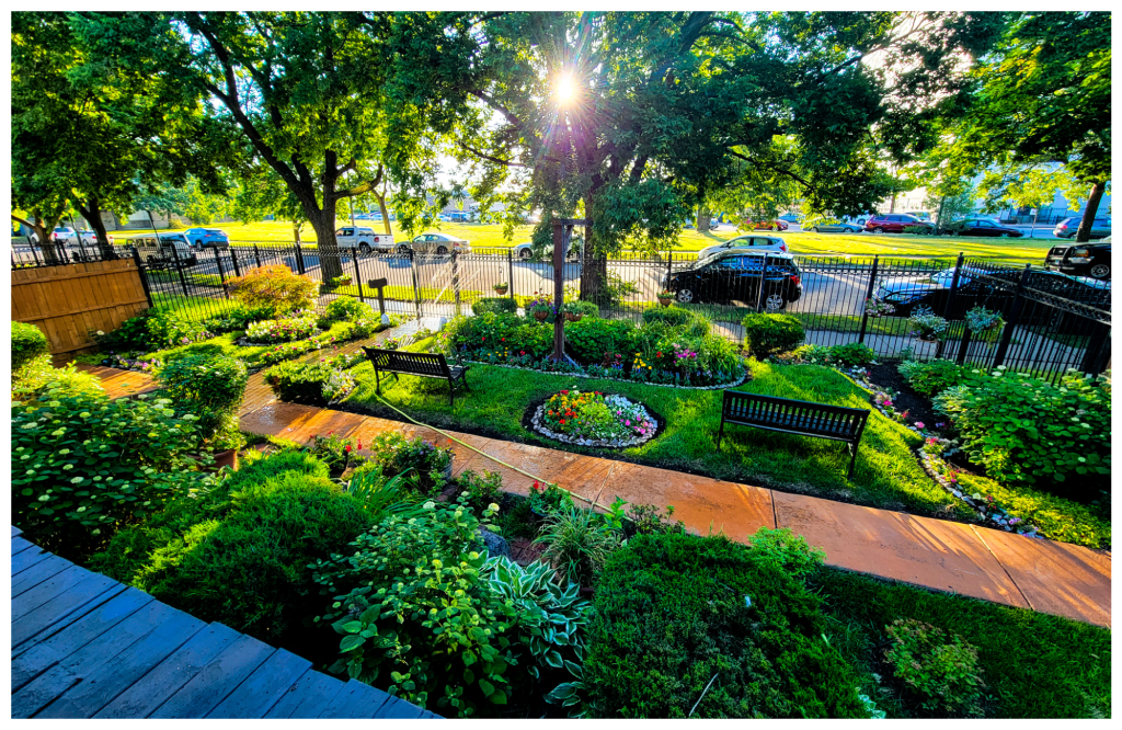 The Perry Mansion garden glowing at golden hour, with winding paths and raised beds.